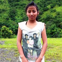 A girl in a white shirt standing on top of a grass covered field.