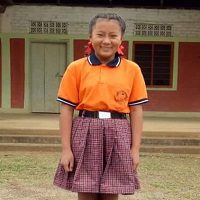A girl in an orange shirt and purple skirt.