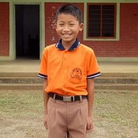 A young boy in an orange shirt and brown pants.