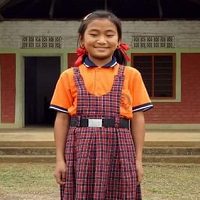 A girl in an orange shirt and plaid skirt.