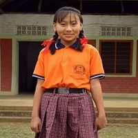 A girl in an orange shirt and purple skirt.