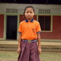 A young girl standing in front of a building.