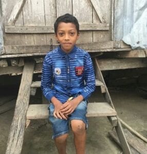 A young boy sitting on top of wooden steps.