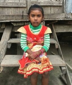 A young girl sitting on top of a wooden bench.