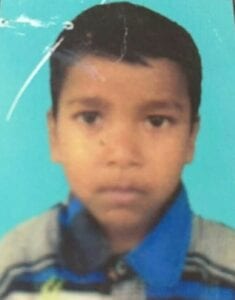 A young boy is standing in front of a blue background.