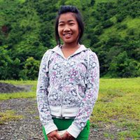 A young woman standing in front of some trees.