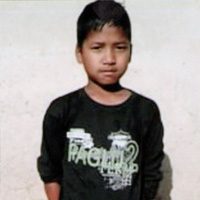 A young boy wearing a black shirt with graffiti on it.
