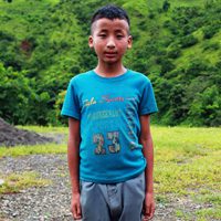 A young boy standing in front of some trees