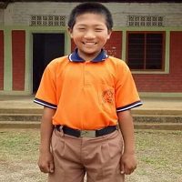 A young boy in an orange shirt and brown pants.