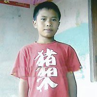 A young boy wearing a red shirt with chinese writing on it.
