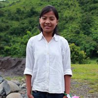 A young girl standing in front of some trees