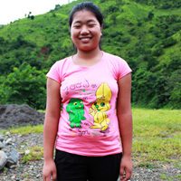 A woman in pink shirt standing on top of a hill.