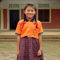 A girl in an orange shirt and plaid skirt.