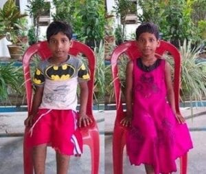 Two children are sitting in red chairs.