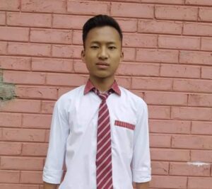A man in a red tie standing next to a brick wall.