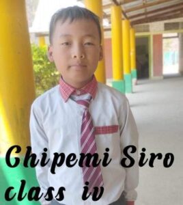 A young boy wearing a tie and standing in front of yellow pillars.