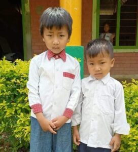 Two boys in white shirts and ties standing next to each other.