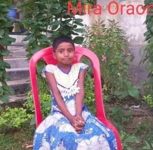 A young girl sitting in a chair outside.