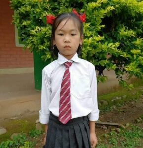 A young girl in school uniform with red hair.