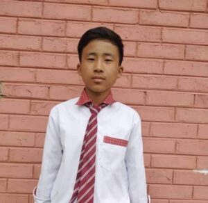 A young man wearing a tie standing in front of a brick wall.