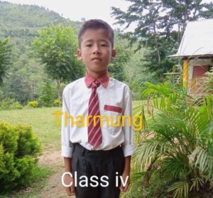A young boy in school uniform standing outside.
