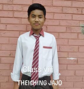 A young man wearing a tie and standing in front of a brick wall.