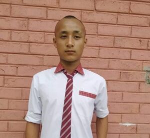 A man in a tie standing next to a brick wall.