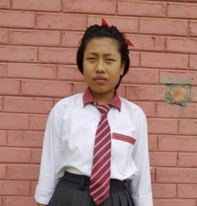 A young girl wearing a tie and pants.