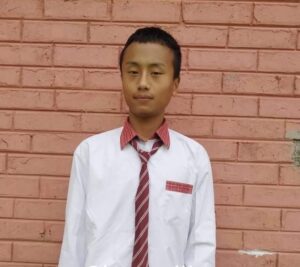 A man in a red tie standing next to a brick wall.