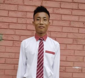 A man in a red tie standing next to a brick wall.