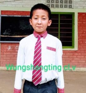 A young boy wearing a tie and standing in front of a building.
