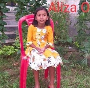 A girl sitting on top of a red chair.