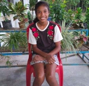 A girl sitting on top of a red chair.