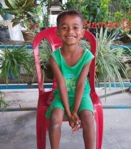 A young boy sitting on top of a red chair.