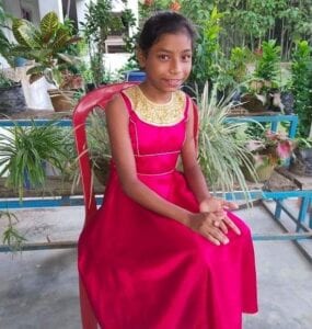 A girl in a red dress sitting on top of a bench.