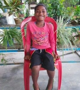 A young boy sitting in a red chair.