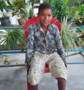 A young boy sitting in a red chair.