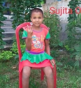 A girl sitting on top of a red chair.