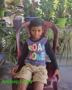 A boy sitting in a chair with plants around him.