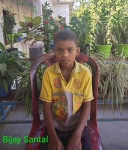A boy sitting in a chair with plants around him.