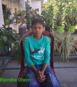A young boy sitting in a chair with plants behind him.