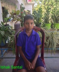 A boy sitting in a chair with plants behind him.