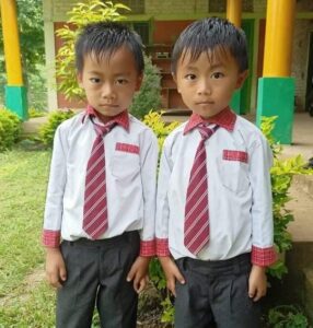 Two young boys in dress clothes standing next to each other.
