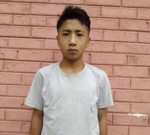 A young man standing in front of a brick wall.