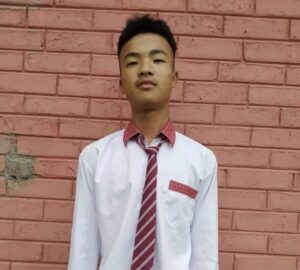 A young man wearing a tie standing in front of a brick wall.