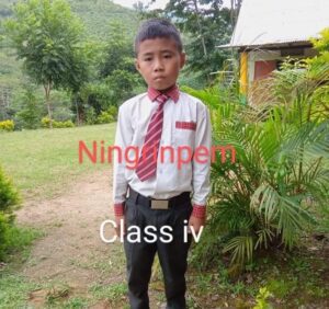 A young boy in a red tie standing outside.