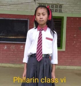 A girl in school uniform standing outside of a building.
