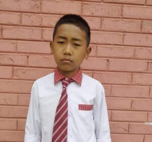 A young boy wearing a red tie and white shirt.