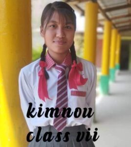 A girl in school uniform standing on the side of a walkway.