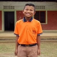 A boy in an orange shirt standing outside.